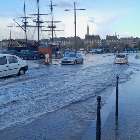 Chaussée inondée d'une route de Saint-Malo. Les voitures roulent dans l'eau.